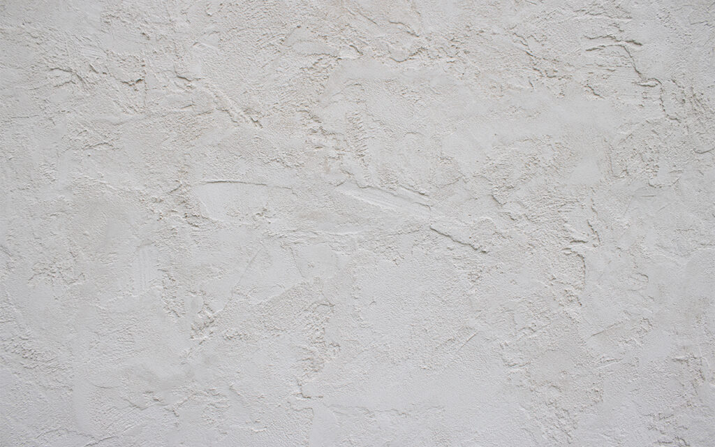 Close-up of a white textured plaster wall surface with irregular patterns and subtle shadows—ideal for showcasing expert stucco crack repair by a professional stucco contractor Twin Cities.