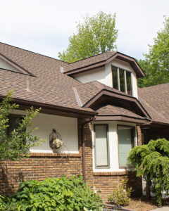 A two-story house with brick and stucco exterior, brown shingle roof, large windows, and green landscaping in front—ideal for those seeking expert stucco crack repair from a trusted exterior contractor in Minnesota.