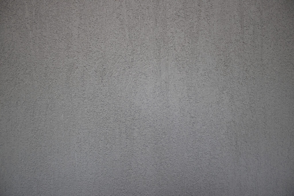A close-up view of a gray, textured concrete wall, ideal for showcasing the expertise of a stucco contractor Twin Cities residents trust.