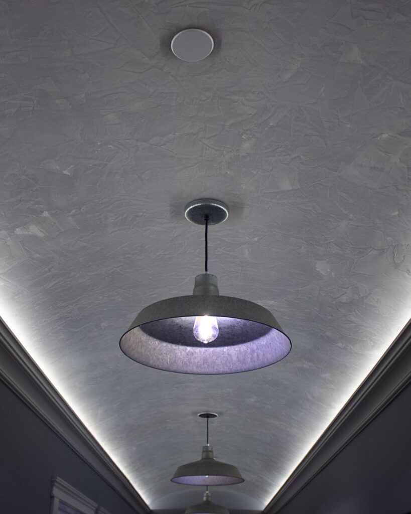 A textured gray ceiling with modern pendant lights and recessed LED strip lighting along the edges—ideal for homes seeking style and durability after moisture remediation stucco or storm damage stucco repair in Minnesota.